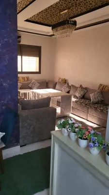 a living room with couches and flowers on a table at Appartement de luxe in Meknès