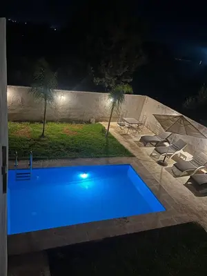 a swimming pool in a yard at night at Maison Royale in Douar bel Rhanodour