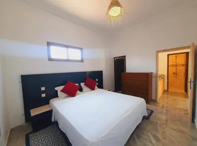 a bedroom with a large white bed with red pillows at Maison Royale in Douar bel Rhanodour