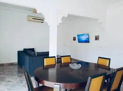 a dining room with a table and chairs and a couch at Maison Royale in Douar bel Rhanodour