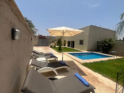 a group of lounge chairs with an umbrella next to a pool at Maison Royale in Douar bel Rhanodour