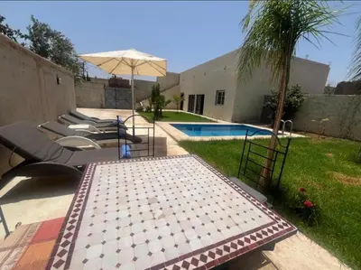 a patio with chairs and an umbrella next to a pool at Maison Royale in Douar bel Rhanodour