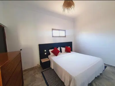 a bedroom with a white bed with red pillows at Maison Royale in Douar bel Rhanodour