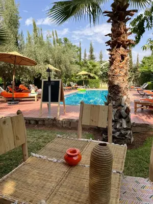 a table and chairs next to a swimming pool at Chambre d'hôtes dans luxueuse villa avec piscine in Had Abdallah Rhiat