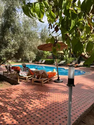 a man laying in a chair next to a swimming pool at Chambre d'hôtes dans luxueuse villa avec piscine in Had Abdallah Rhiat