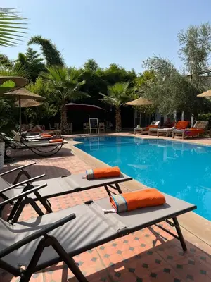 a swimming pool with chaise lounges and umbrellas at Chambre d'hôtes dans luxueuse villa avec piscine in Had Abdallah Rhiat