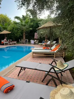 a pool with chairs and an umbrella and a table at Chambre d'hôtes dans luxueuse villa avec piscine in Had Abdallah Rhiat