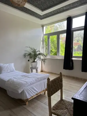 a bedroom with a bed and a large window at Chambre d'hôtes dans luxueuse villa avec piscine in Had Abdallah Rhiat