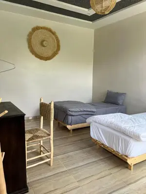 a room with two beds and a table and a chair at Chambre d'hôtes dans luxueuse villa avec piscine in Had Abdallah Rhiat