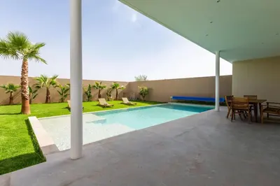 a swimming pool in a house with a table and chairs at Villa Seyana 3 sans vis a vis, Piscine Chauffee in Marrakech