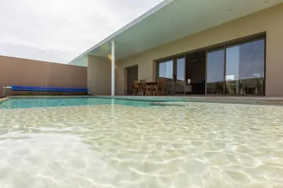 a large swimming pool with a house with glass windows at Villa Seyana 3 sans vis a vis, Piscine Chauffee in Marrakech