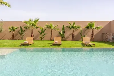 two chairs and a swimming pool with palm trees at Villa Seyana 3 sans vis a vis, Piscine Chauffee in Marrakech
