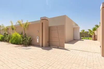 a building with two garage doors on a brick driveway at Villa Seyana 4 sans vis a vis, Piscine Chauffee in Marrakech