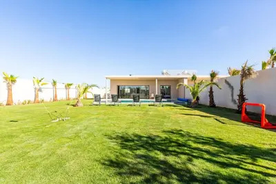 a house with a large yard with palm trees at Villa Seyana 7 Zero Vis a Vis, Piscine Chauffee in Gzoula