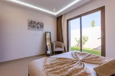 a bedroom with a bed and a window and a chair at Villa Seyana 7 Zero Vis a Vis, Piscine Chauffee in Gzoula