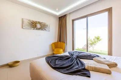 a bedroom with a bed with a window and a yellow chair at Villa Seyana 7 Zero Vis a Vis, Piscine Chauffee in Gzoula
