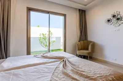 a bedroom with a bed and a window and a chair at Villa Seyana 8 Zero Vis a Vis Piscine Chauffee in Gzoula