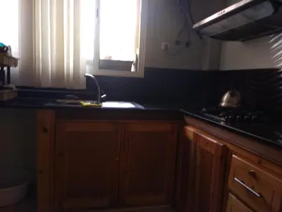 a kitchen with wooden cabinets and a sink and a window at Appartement bien équipé in Ifrane