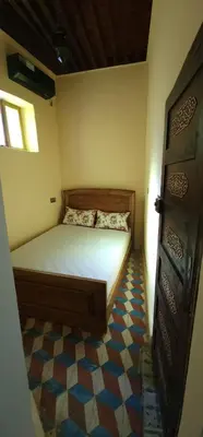a small bedroom with a bed and a tiled floor at The hostel with terrace view in Fès
