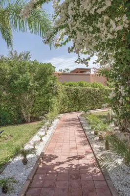 a brick path in a garden with trees and bushes at Villa AIMA - avec Gourvernante in Douar Soukkane