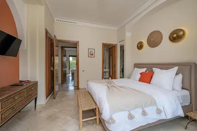 a bedroom with a bed and a desk and a television at Villa AIMA - avec Gourvernante in Douar Soukkane