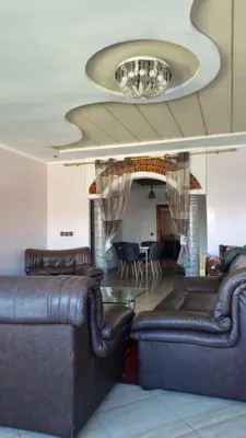 a living room with leather furniture and a chandelier at Bel appartement en plein Taza in Taza