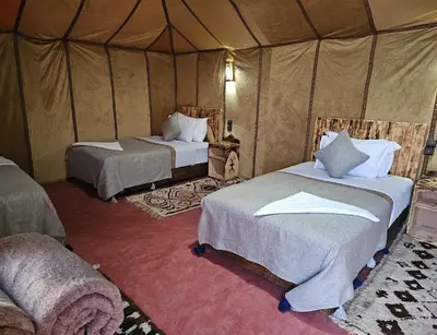 a bedroom with two beds in a tent at Sandside Luxury Camp in Merzouga