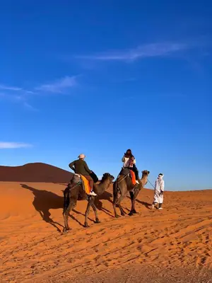 a group of people riding horses in the desert at Sandside Luxury Camp in Merzouga