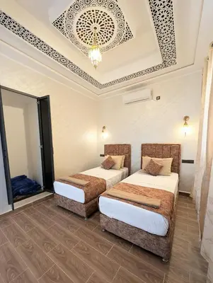 a room with two beds and a chandelier at Luxury Merzouga Appartement in Merzouga