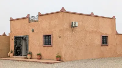 a brown building with plants in front of it at Luxury Merzouga Appartement in Merzouga