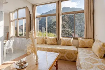 a living room with a couch and large windows at Maison authentique Ourika avec vue sur l'Atlas in Ourika