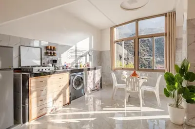 a kitchen with a dishwasher and a table with chairs at Maison authentique Ourika avec vue sur l'Atlas in Ourika