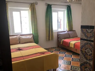 two beds in a room with two windows at Dar Kakun in Oulad Akkou