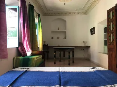 a bedroom with a bed and a table and a chair at Dar Kakun in Oulad Akkou