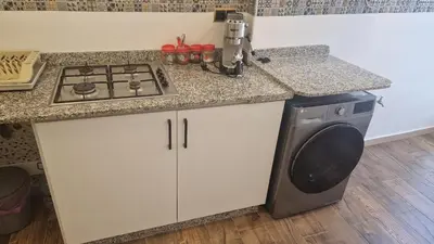 a kitchen with a stove and a washing machine at Princière Downtown apartment, Fiber optic in Oulad Akkou