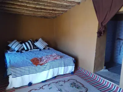 a bedroom with a bed in a room with a rug at Planet Camp Désert Tours in Mhamid