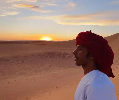 a man in the desert watching the sunset at Planet Camp Désert Tours in Mhamid