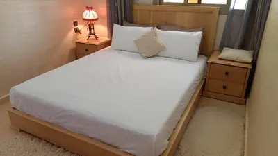 a bedroom with a large white bed with two night stands at Appartement de céder in Azrou