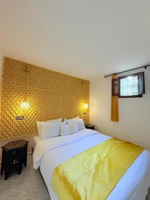 a bedroom with a large white bed and a window at Riad Dar Mazaj Fes in Fès