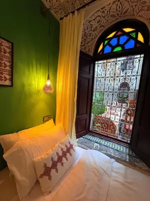 a bedroom with a bed and a stained glass window at Riad Dar Mazaj Fes in Fès