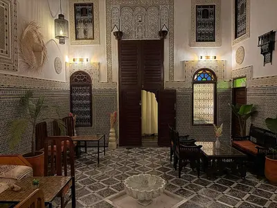 a room with a table and chairs and a door at Riad Dar Mazaj Fes in Fès