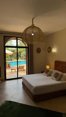 a bedroom with a bed with a view of a pool at Hacienda de Julie in Sraïri