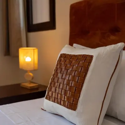 a brown and white pillow on a bed with a lamp at Hacienda de Julie in Sraïri