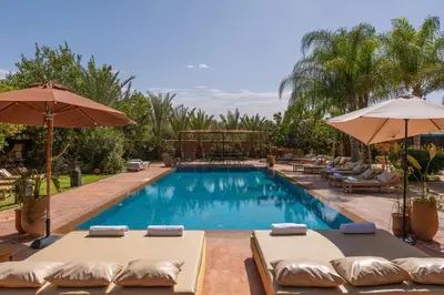 a swimming pool with lounge chairs and umbrellas at Hacienda de Julie in Sraïri