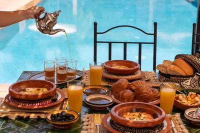 a table full of food and drinks and a person pouring juice at Hacienda de Julie in Sraïri