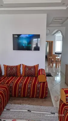 a living room with a couch and a tv on the wall at maison 83 in Oulad Akkou