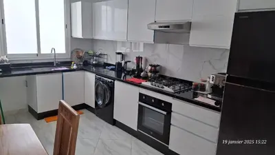 a kitchen with white cabinets and a stove and a dishwasher at maison 83 in Oulad Akkou