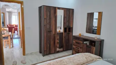 a bedroom with a wooden dresser and a mirror at maison 83 in Oulad Akkou