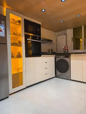 a kitchen with white cabinets and a washer and dryer at Illy house in Ifrane