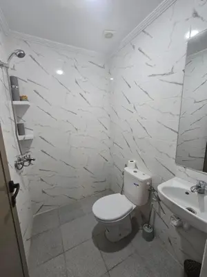 a white bathroom with a toilet and a sink at Narjiss Hostel in Fès